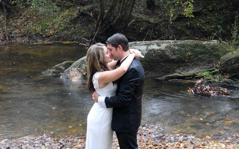 Bride and groom kissing by a stream